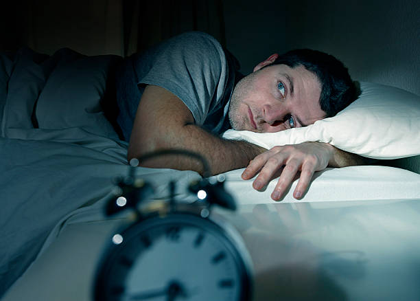 man in bed eyes opened suffering insomnia and sleep disorder stock photo