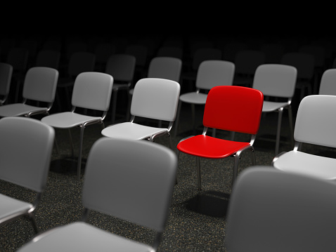 Group of chairs with a red chair standing out symbol for uniqueness