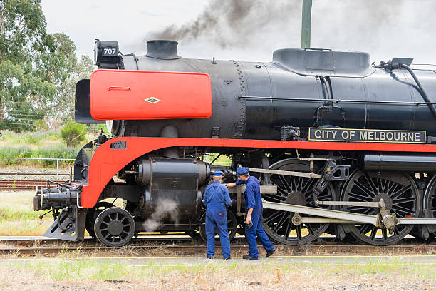 Melbourne, Australia - October 17, 2015: Close-up of two engineers checking the engine of steam locomotive R707, named the 'City of Melbourne' in a railway station in Melbourne before its departure.