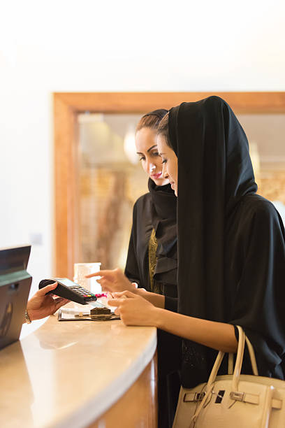 Traditionell gekleideten emiratischen Frau bezahlen mit Kreditkarte an der Theke – Foto