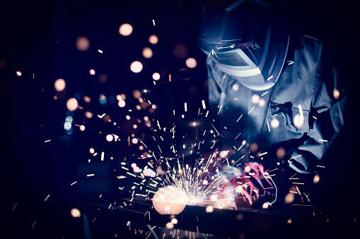 Employee welding steel with sparks, using MiG MAG welder