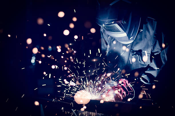 Employee welding steel Employee welding steel with sparks, using MiG MAG welder metalwork stock pictures, royalty-free photos & images