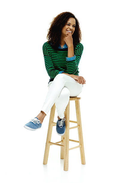 Cheerful woman sitting on stool & looking away