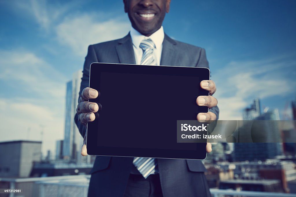 Businessman with digital tablet Cropped shot of businessman standing on the rooftop with the view over the London City and holding a digital tablet. Digital Display Stock Photo