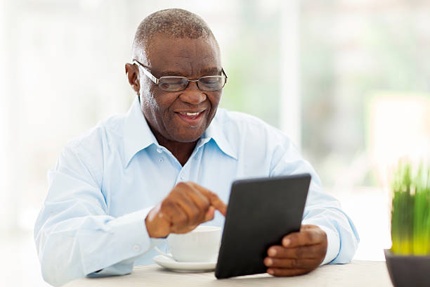 senior afrikanischen amerikanischen mann mit tablet pc zu hause fühlen - nur ein mann mittleren alters stock-fotos und bilder