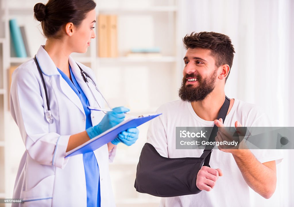 Injury man in doctor Injury hands. Young man with injured hands. Young woman doctor helps the patient 2015 Stock Photo