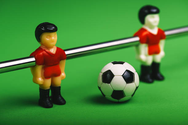 A group of wooden soccer players are lined up on a green field