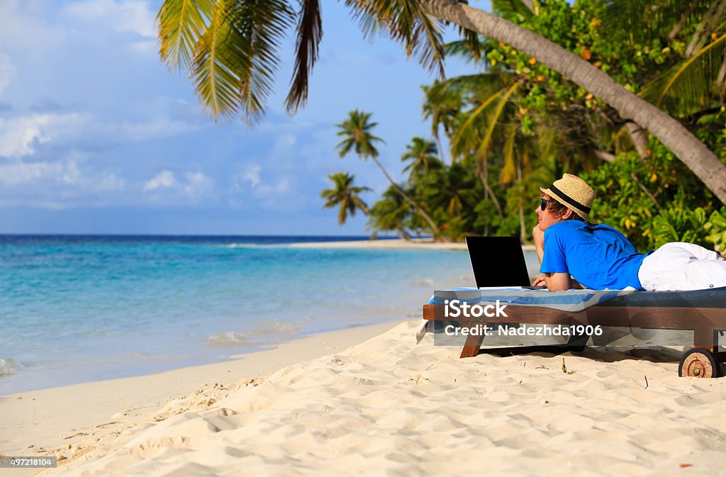 young man with laptop on tropical beach young man with laptop on tropical beach vacation 2015 Stock Photo