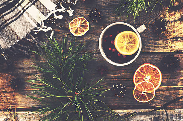 Winter drink with lemon, cranberries and spices Winter drink with lemon, cranberries and spices, pine tree twigs and checked plaid on wooden background pine needle tea stock pictures, royalty-free photos & images