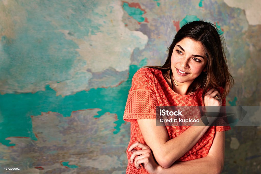 She's an easygoing girl! Shot of a smiling young woman standing in front of a a peeling wall Cool Attitude Stock Photo