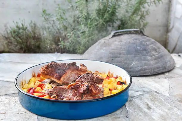 Cooking of traditional balkan turkish bosnian dalmatian meal Peka in metal pots called sac sach or sache. Traditional roast of pork beef or veal. Soft focus - shallow depth of field