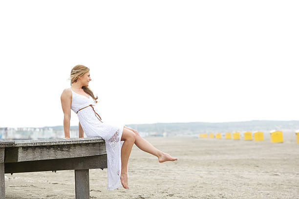 istock Young woman sitting alone at the beach 497225809