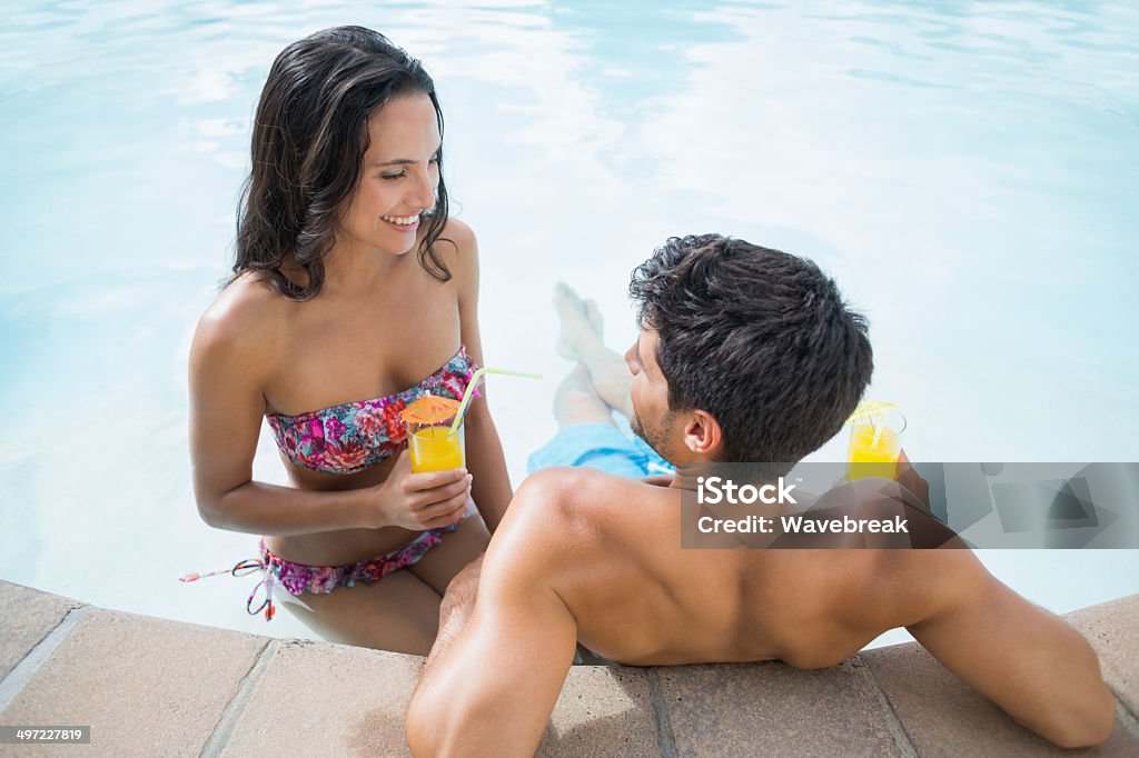 Attractive couple drinks cocktails Attractive couple drinks cocktails outside by pool 20-29 Years Stock Photo