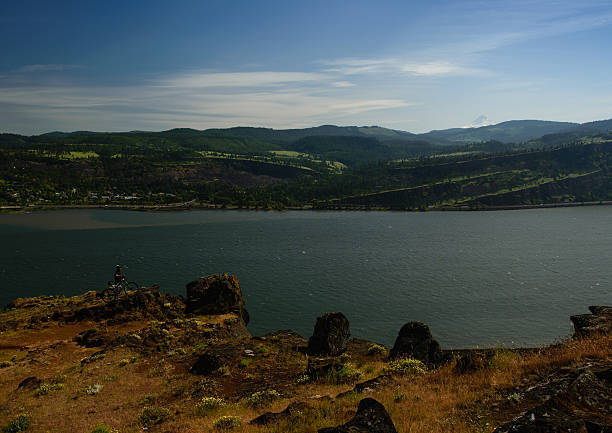 Mountain bikers, River & Mountain Mountain biker standing at the edge of a cliff looking at a view of Mt Hood and Columbia River, Oregon, WA, USA syncline stock pictures, royalty-free photos & images