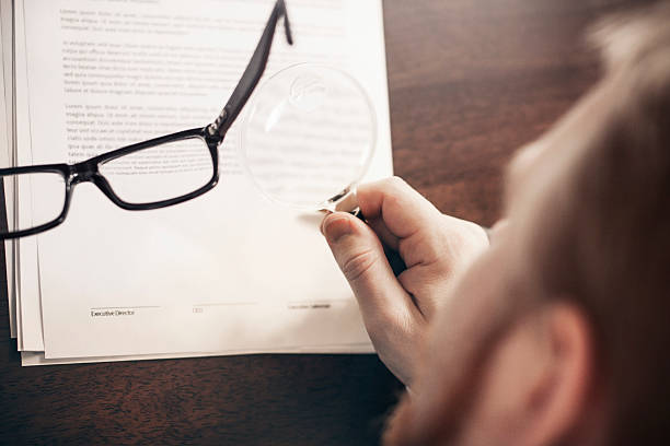 Small Print Inspecting Agreement with Magnifying Glass read the fine print stock pictures, royalty-free photos & images