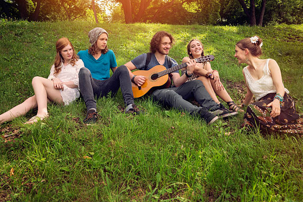 istock Group of young people singing and playing guitar in park. 497232191