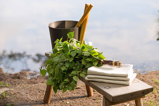 Sauna objects on wooden bench before lake at summer birch whisk used in sauna on wooden bench by lake in Finland at summer. Sauna objects before lake. swedish sauna stock pictures, royalty-free photos & images