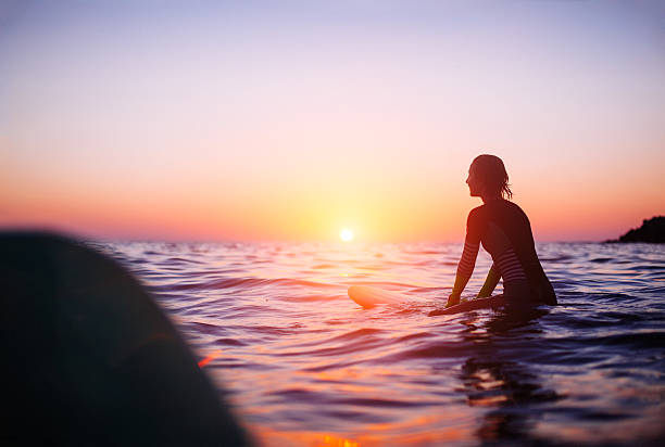 surfer girl surfer girl sitting on surfboard in ocean, sunset. beautiful mexican girls stock pictures, royalty-free photos & images