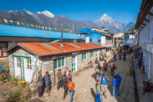 Crowds of Nepali porters, Sherpa mountain guides and Western trekkers milling around the main street of Lukla, the colourful village of teahouses, lodges and shops high in the Himalaya mountains of Nepal. ProPhoto RGB profile for maximum color fidelity and gamut.