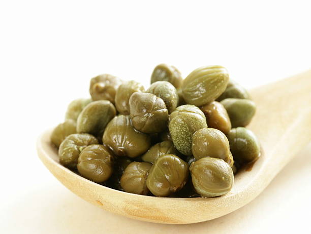 istock Pickled gourmet green capers in a wooden spoon 497241047