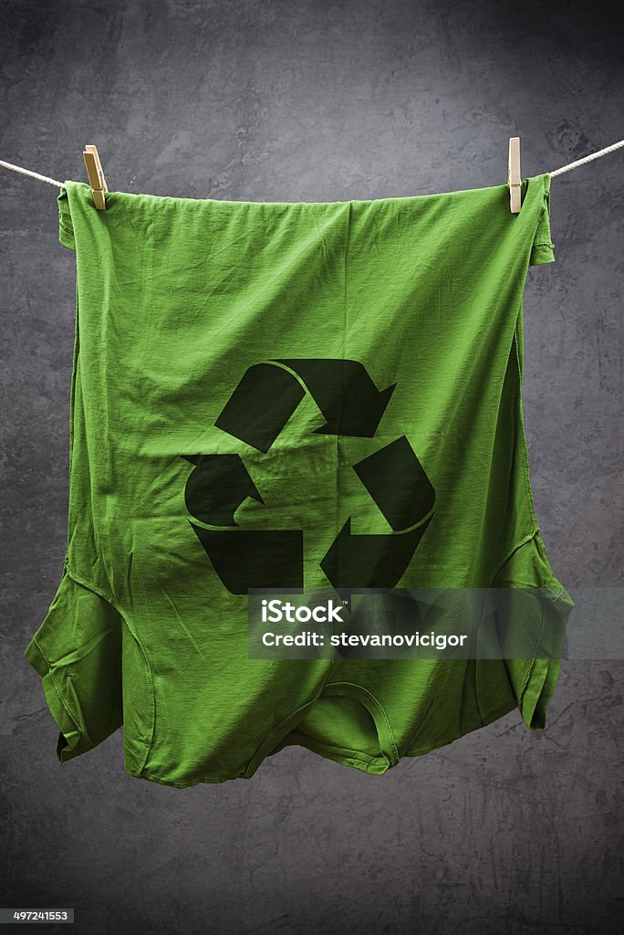 Green t shirt with recycle symbol Green t shirt with Recycle symbol hanging on rope to dry, attached with clothes pins. Alertness Stock Photo