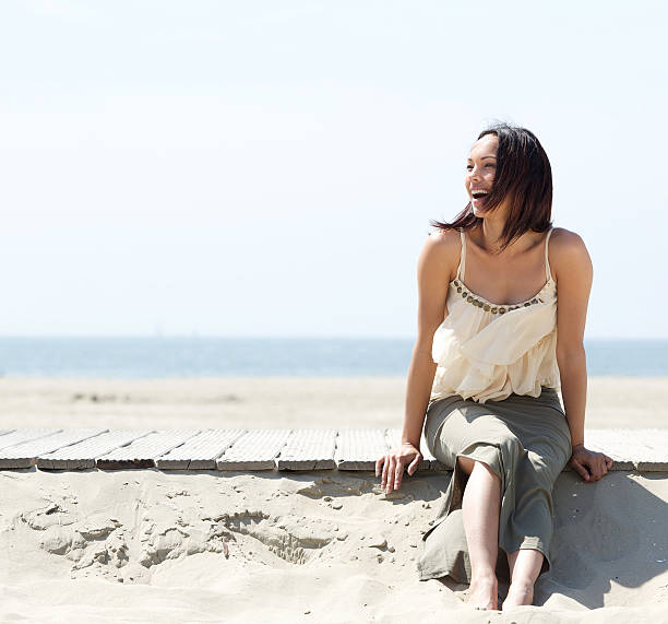 istock Cheerful young woman sitting by the beach 497242975