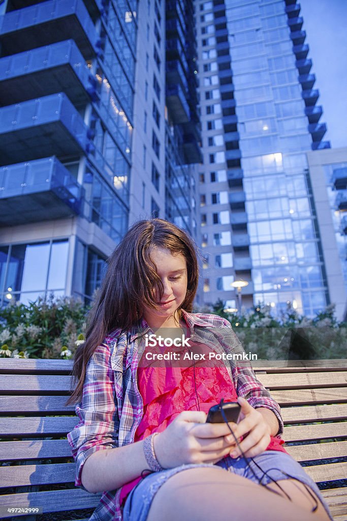 Teenager girl read something at smart phone Teenager girl read something at smart phone. She sits at the bench in Williamsburg district close to a pier, Brooklyn, New York,  Architecture Stock Photo