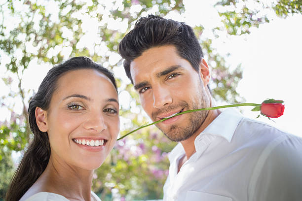Couple with red rose smiles at camera in garden