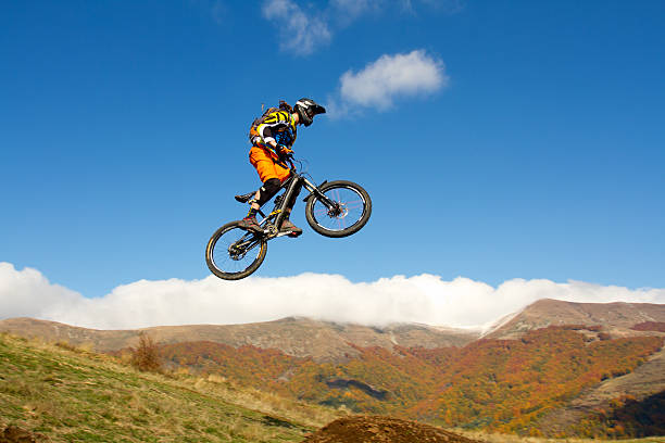 Mountain biker in the air, skipping a gap, during an enduro trail riding in a beautiful autumn day.