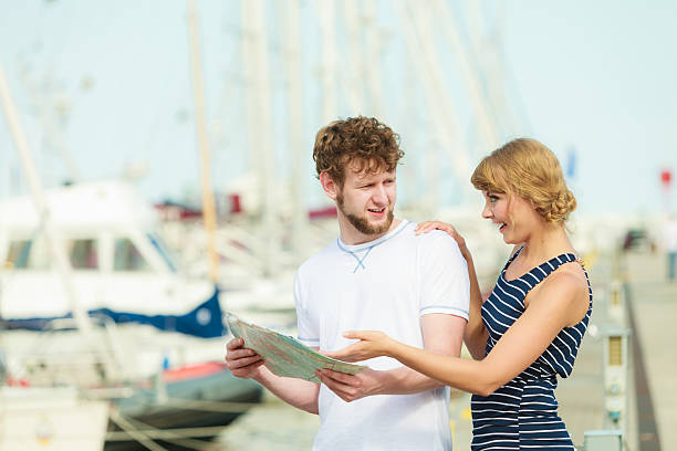 istock Tourist couple in marina looking up directions on map 497252412