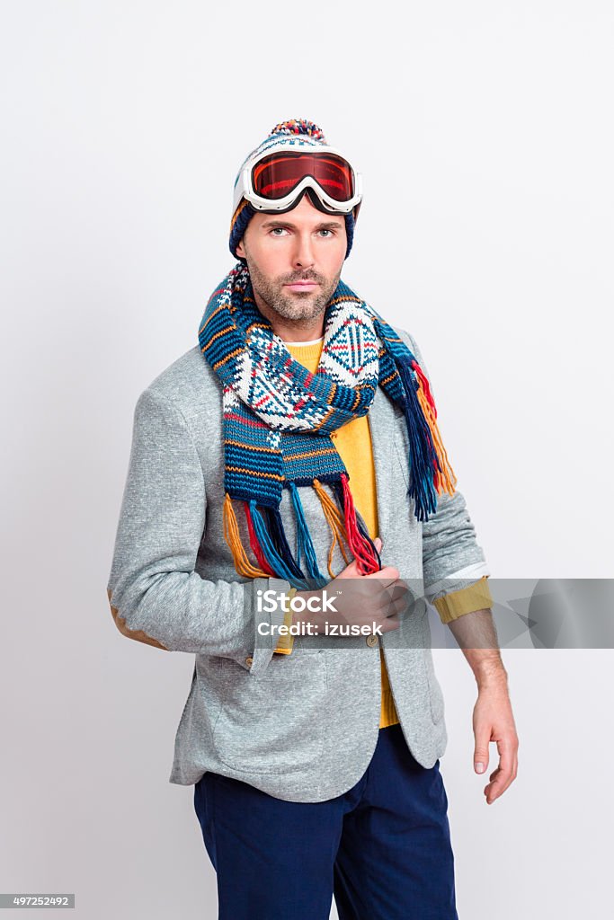 Handsome man in winter outfit Studio portrait of handsome man in winter outfit - cap, scarf and goggles, standing against white background and looking at camera. Skiing Stock Photo