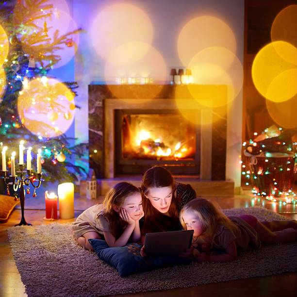 Mother and daughters using tablet by a fireplace on Christmas