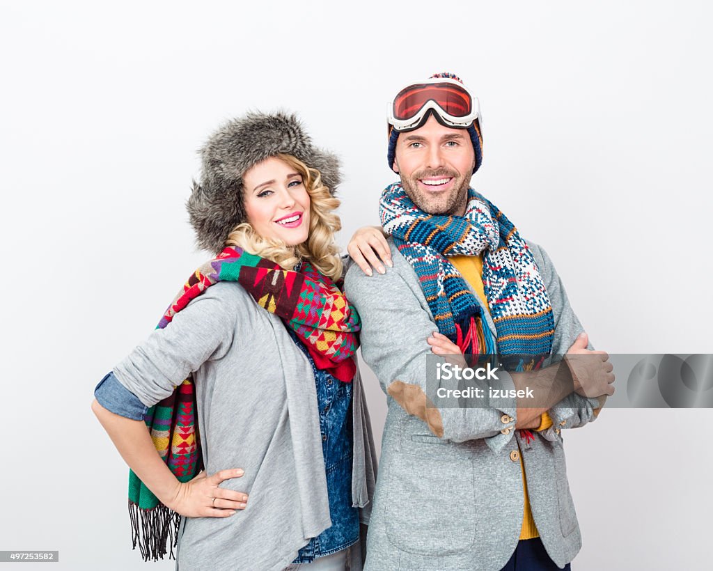 Happy couple in winter outfit against white background Studio portrait of happy couple in winter outfits - caps, scarfs, sweaters, laughing at camera.  2015 Stock Photo