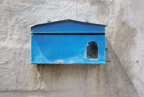 blue mailbox front of old cement wall of home