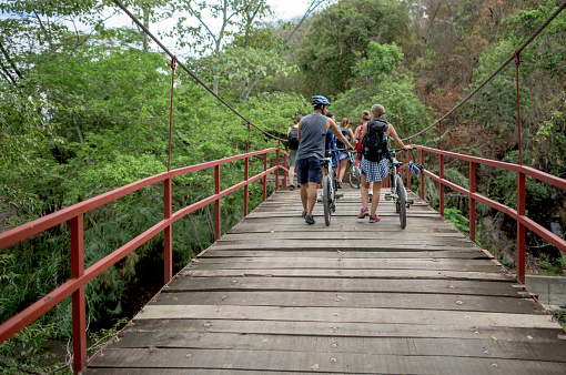 Group of mountain bikers crossing a bridge on foot but holding their bikes