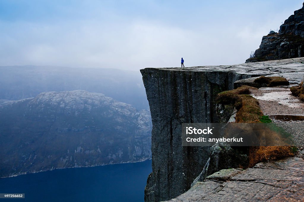 travel to Norway, person looking on the fjords power of nature, small person on big cliff Cliff Stock Photo
