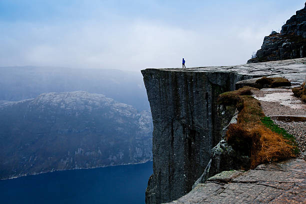 travel to Norway, person looking on the fjords power of nature, small person on big cliff majestic stock pictures, royalty-free photos & images