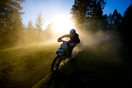 A male motocross rider hits a dusty trail in British Columbia, Canada at sunset.