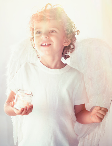 Smiling angel holding a candle in a glass and looking away