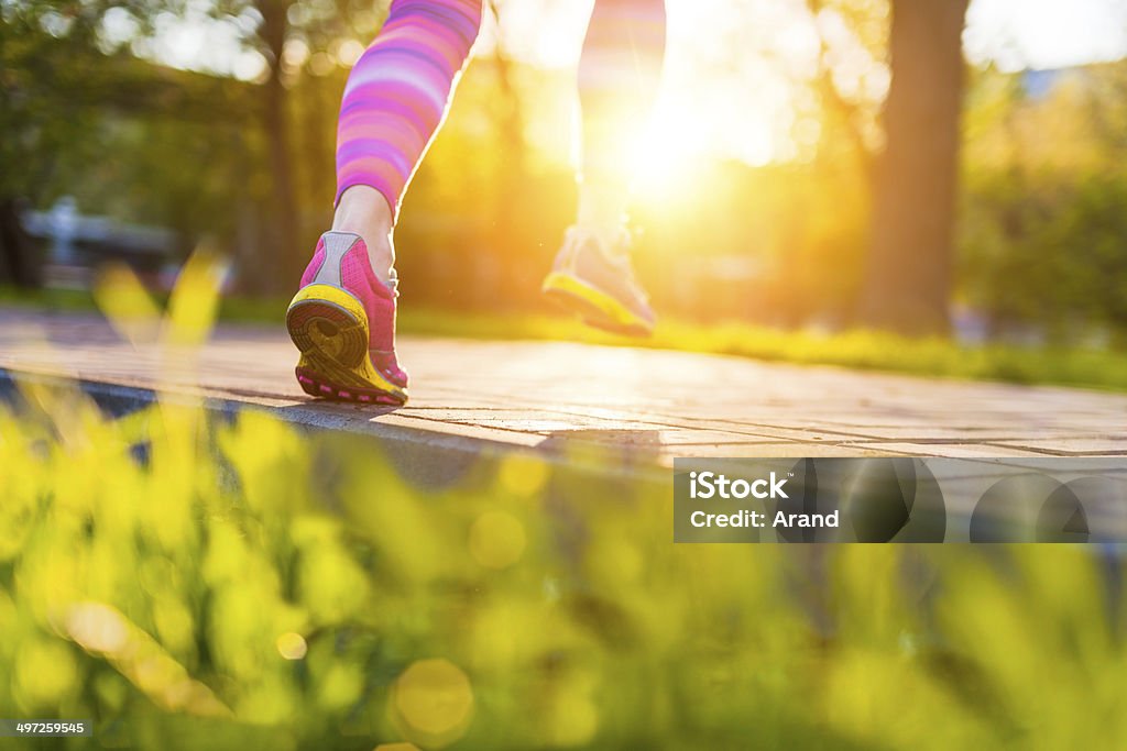 Runner feet. Runner feet on footpath closeup on shoe sole. Sunset, lens flare. Jumping Stock Photo