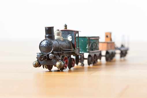 Cute little tin toy locomotive at full speed. Close-up view on a wooden floor.
