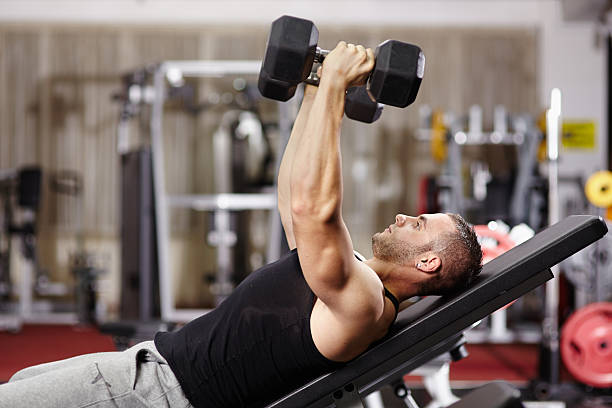 Athletic man working his chest Athletic young man laid on back working his chest with heavy dumbbells chest dumbbells ripl fitness