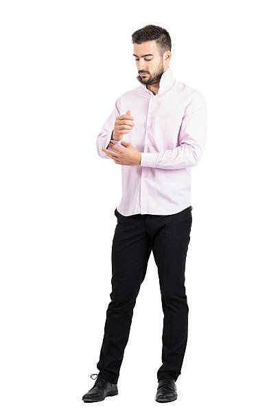 Young elegant man in pink shirt buttoning his sleeves.