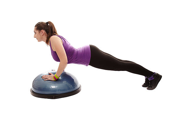 Athletic woman doing pushups on a bosu ball stock photo
