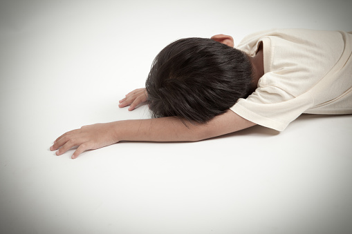 asian boy kid lying down on white floor like accident or fainting