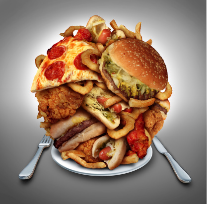 Fast food diet concept served on a plate as a mountain of greasy fried restaurant take out as onion rings burger and hot dogs with fried chicken french fries and pizza as a symbol of compulsive overeating and dieting temptation resulting in unhealthy nutrition.