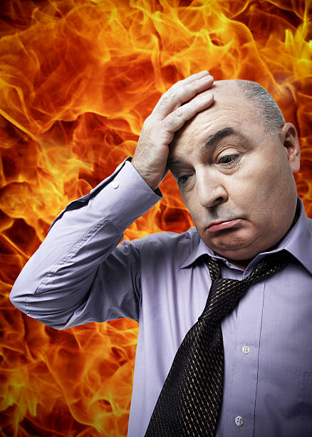 istock Frustrated businessman with hand on head standing against fire 497272127