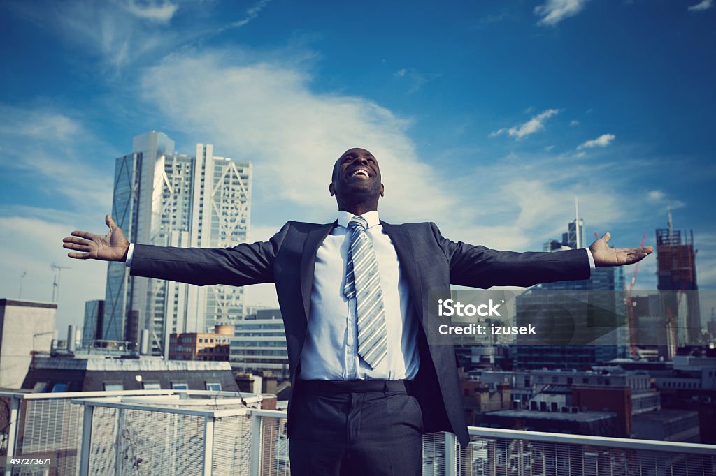 Freedom Excited businessman standing with arms outstretched on the rooftop with the view over the London City. Financial Occupation Stock Photo