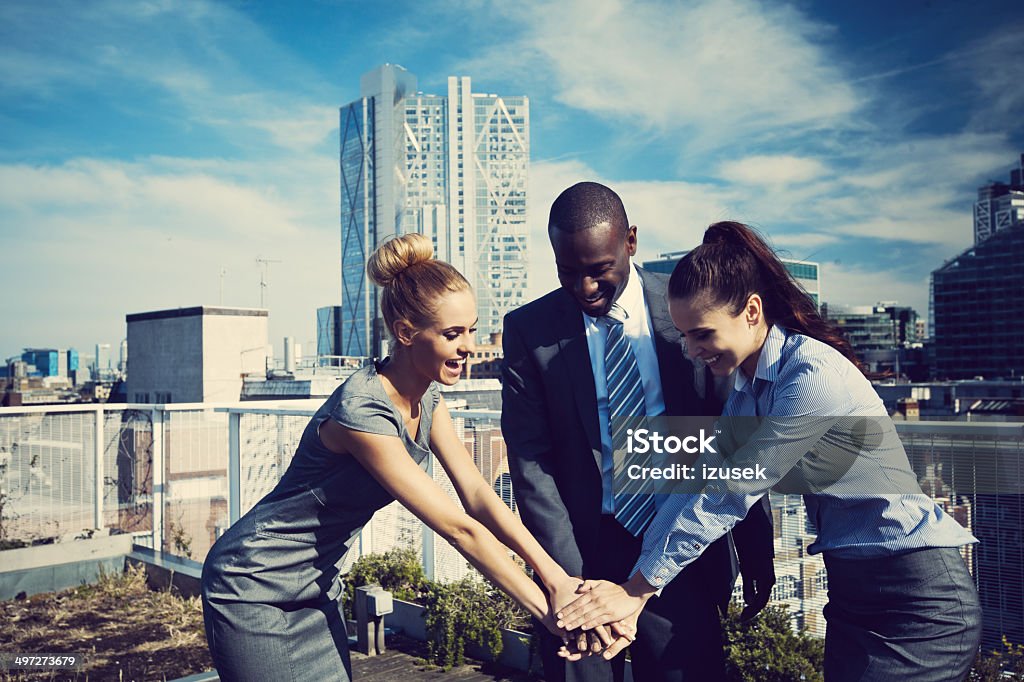Agreement Happy business people standing on the rooftop with the view over the London City and joining their hands. Business Stock Photo