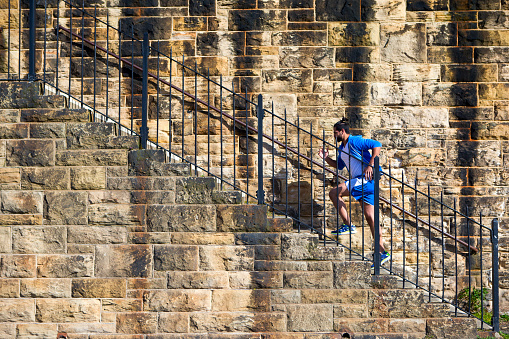 Side shot of a male running up a staircase by a brick wall.